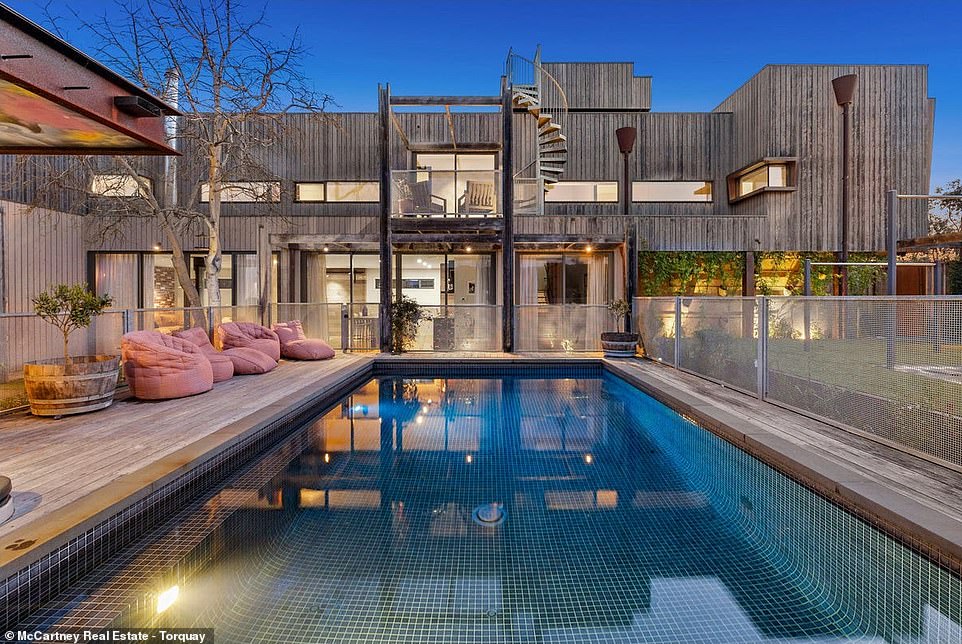 The pool area is surrounded by metal fencing that matches the industrial chic theme of the home and features an expansive heated pool, spa and area to lounge in the sun.