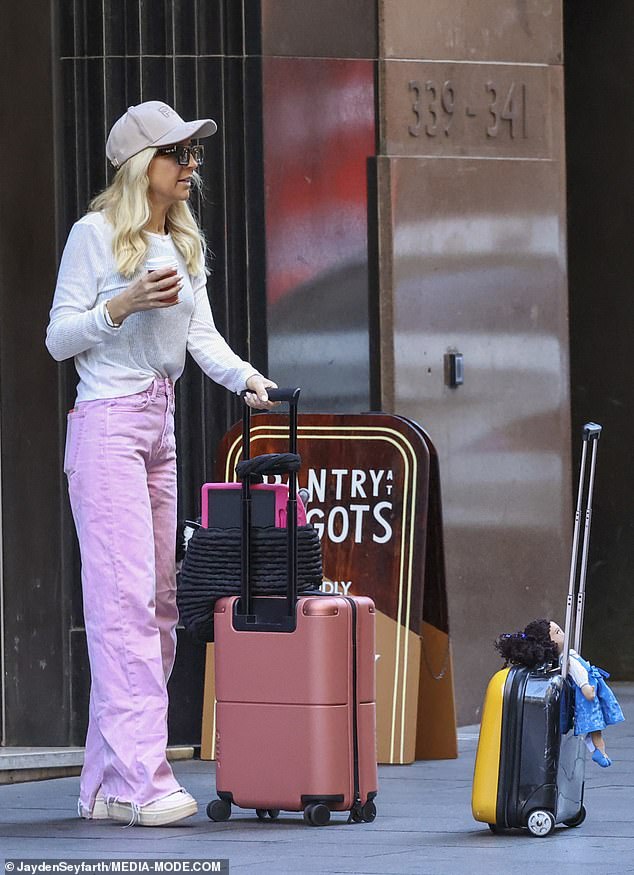 She rolled a coral-colored suitcase along the sidewalk outside the hotel as she placed a black bag on top of it, full of children's toys.