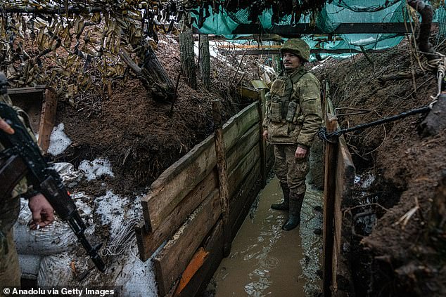 A Ukrainian infantryman stands guard in the trenches on the front line, towards Bakhmut