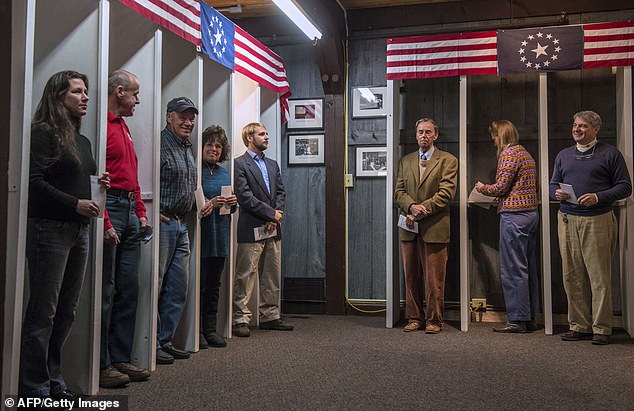 A dozen voters prepare to cast their ballots at voting booths at midnight on November 6, 2012 in Dixville Notch, New Hampshire.  Since then, the electorate in the New Hampshire city has been halved