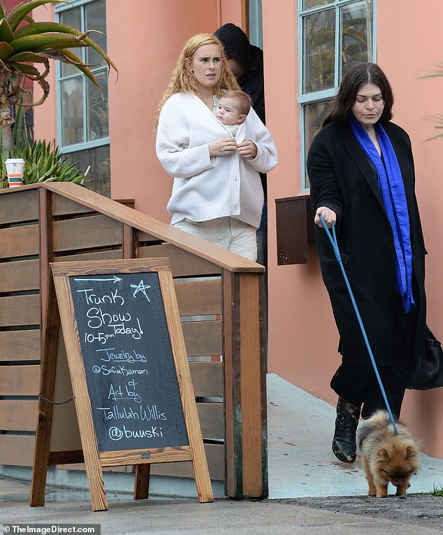 Her bright blonde fell on her shoulders and she held her baby daughter Louetta, who arrived last April, in a breast carrier during her visit to the pop-up