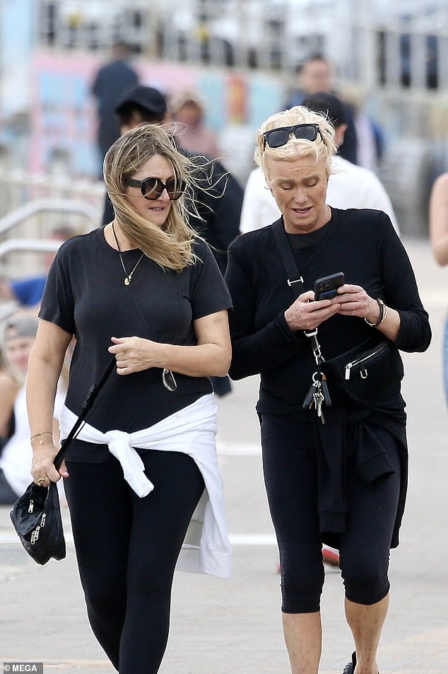 A strong wind blew around the couple as Deborra-Lee tried to show her companion something on her phone