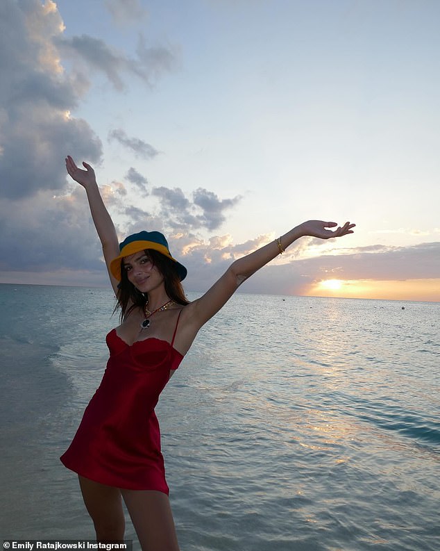 In the cover photo of her series, she again posed on the coast in front of a colorful sky, but this time in a little red slip dress and a colorful bucket hat