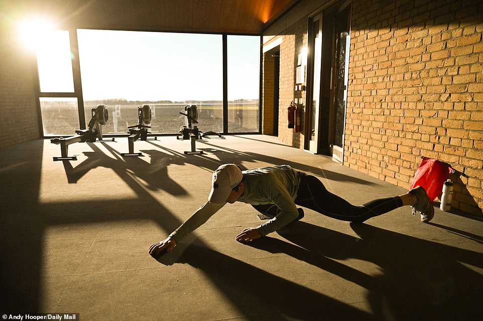 The crew begins their warm-up before hitting the water as the sun shines through the gym