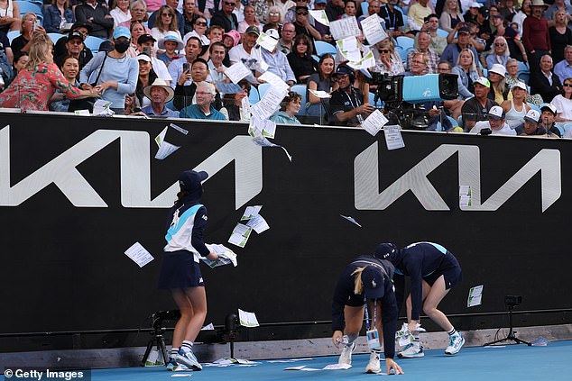 Staff bent down to clear the leaflets from the pitch during an enforced stoppage in play at Margaret Court