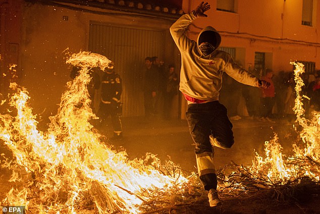 A man jumps over the fire during the Matxa portion of it during the Saint Antoni festival