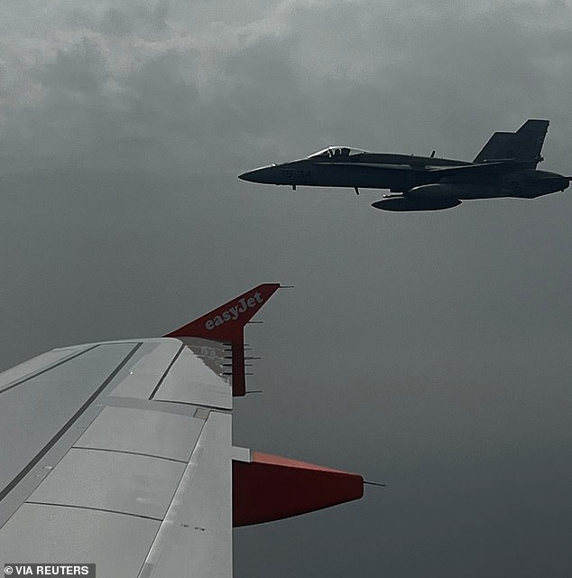 Spanish F-18 fighter jet, seen through plane window, escorts an Easyjet flight en route from London to the Spanish holiday island of Menorca, following a hoax bomb threat by Verma on July 3, 2022