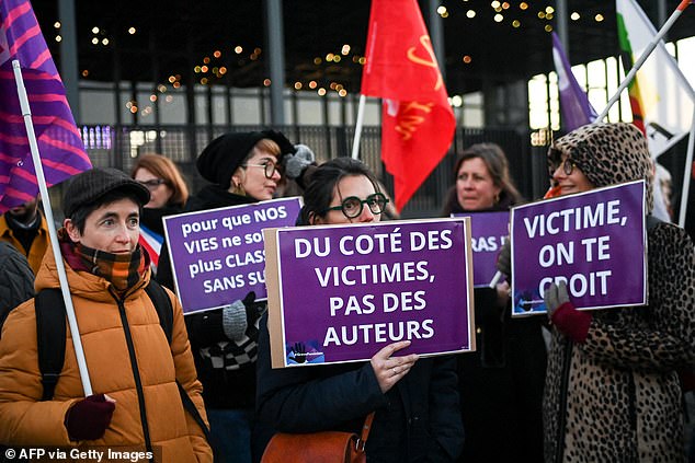 A feminist activist holds a sign reading 