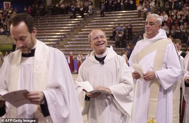 Rev.  Gene Robinson (center) smiles at the crowd during the opening procession of his ordination as coadjutor bishop of the Episcopal Diocese of New Hampshire