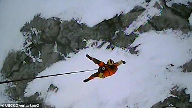 A Coast Guard member is seen being lowered onto the ice floe to rescue the stranded fishermen