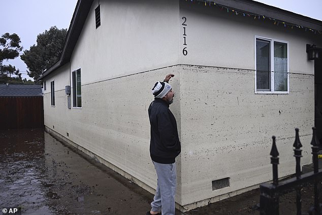 Juan Gonzales gestures to the water line of a flooded house during a rainstorm