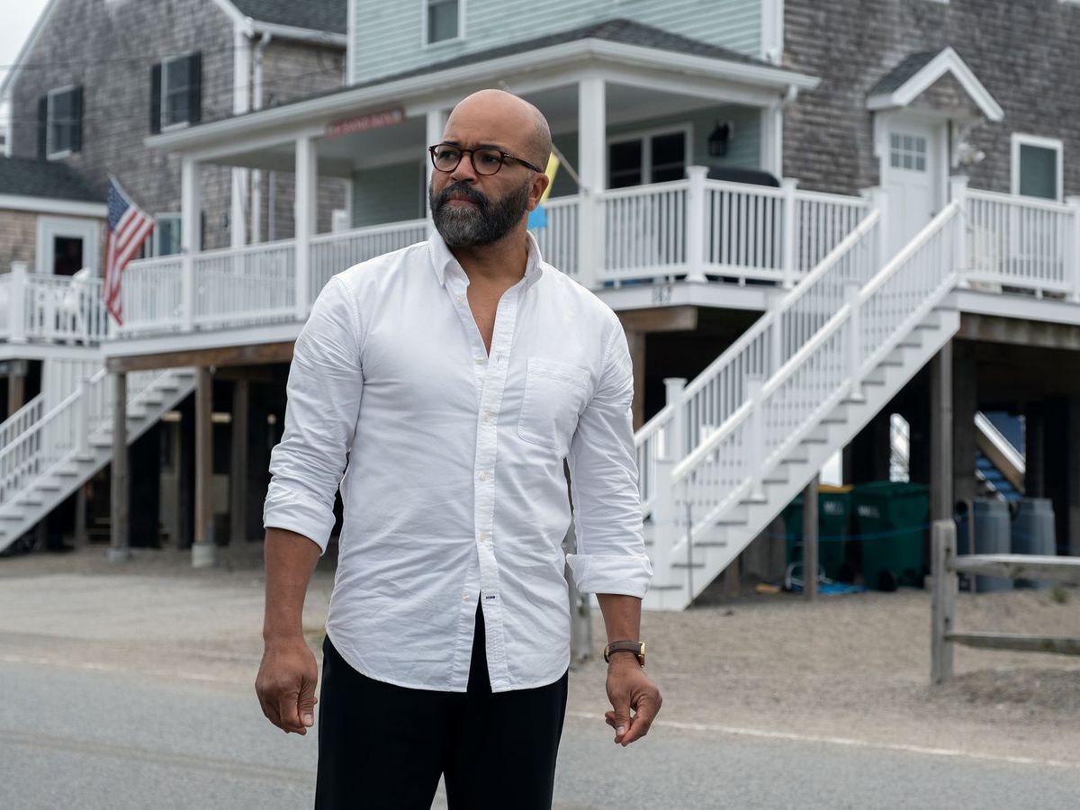 A man in a white button-up shirt (Jeffrey Wright) standing in front of elevated houses near a beach in American Fiction.