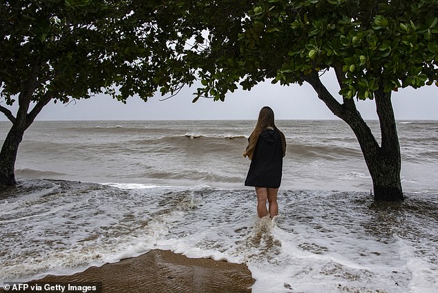 The cyclone is expected to be followed by devastating flooding, with up to a meter of rain falling in some areas (Photo: A Holloways Beach resident as Cyclone Jasper approaches landfall in Cairns in far north Queensland on December 13)