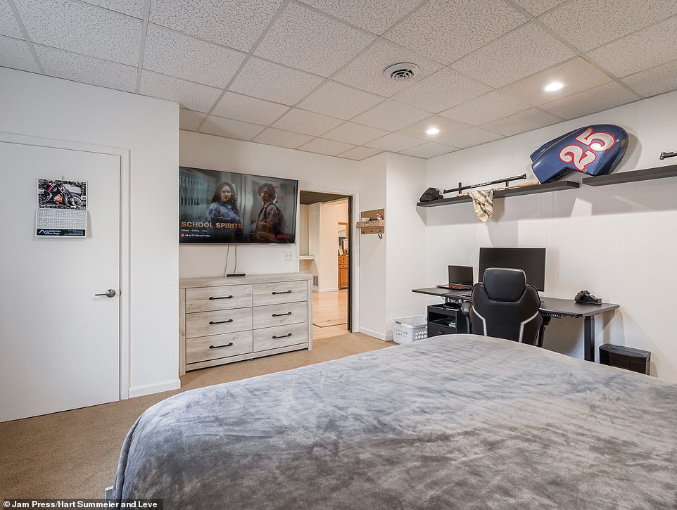 The room has gray and black details and offers plenty of space for wall shelves and an office space and extra storage space