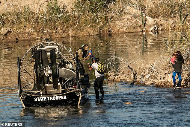 A migrant family is picked up by a member of the Texas Department of Public Safety after being stranded on the riverbank for hours in Eagle Pass, Texas