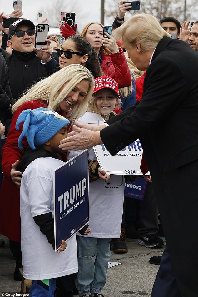 Former President Donald Trump (right) greets a young supporter during a surprise stop at a polling station in Londonderry on Tuesday.  Representative Marjorie Taylor Greene (left) stood next to the former president