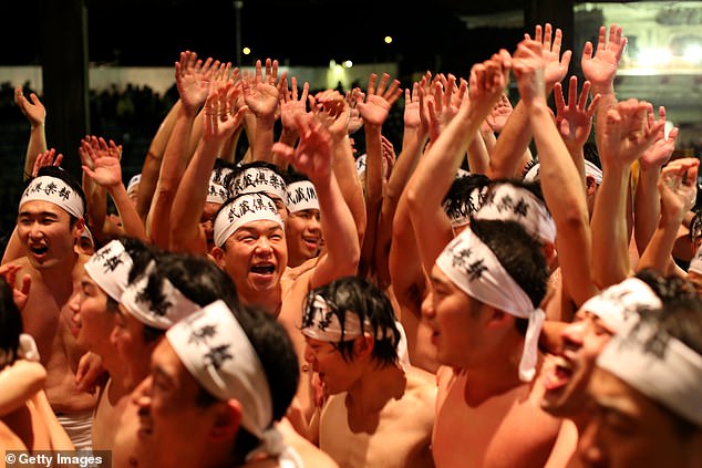 Revelers cheer as they gather in the temple building while catching a sacred wooden stick at the Naked Festival