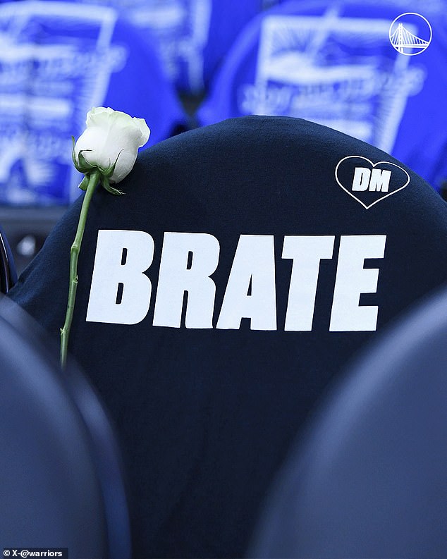 The team reserved a seat on the bench for the coach and placed a 'BRATE' shirt and flower over it