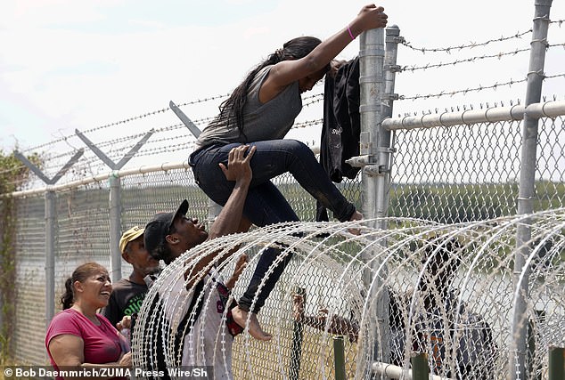 A group of migrants from Colombia, Honduras and Guatemala successfully scale a border fence into the United States south of Eagle Pass, Texas