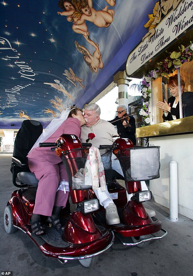 Charolette Richards applauds from the drive-through window as Sasha Semenoff plays a violin in the background