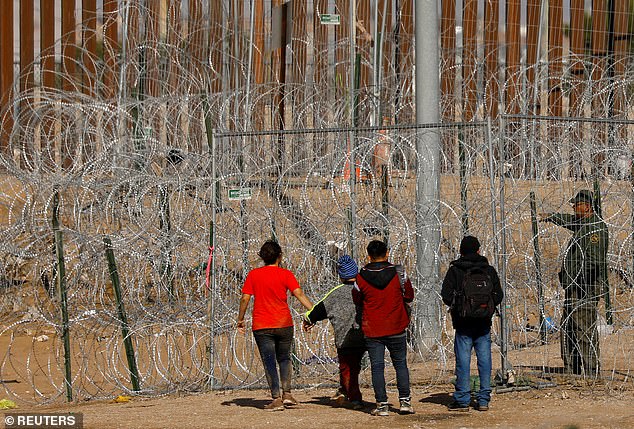 Migrants seeking asylum in the US gather near barbed wire set up to impede the crossing of migrants into the US as they attempt to be processed by US Border Patrol in El Paso, Texas, seen from Ciudad Juarez, Mexico on January 23.  2024