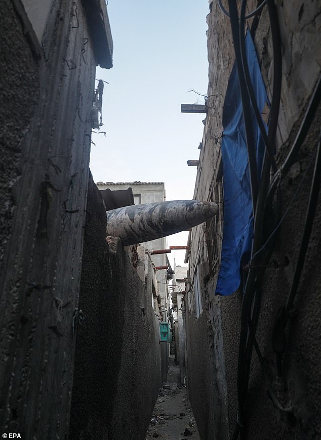 An unexploded rocket is seen stuck between two houses of Al Nusairat refugee camp during Israeli operations in the southern Gaza Strip