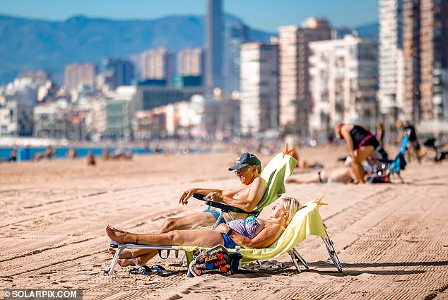 A couple sunbathing on the beach in Benidorm, Spain