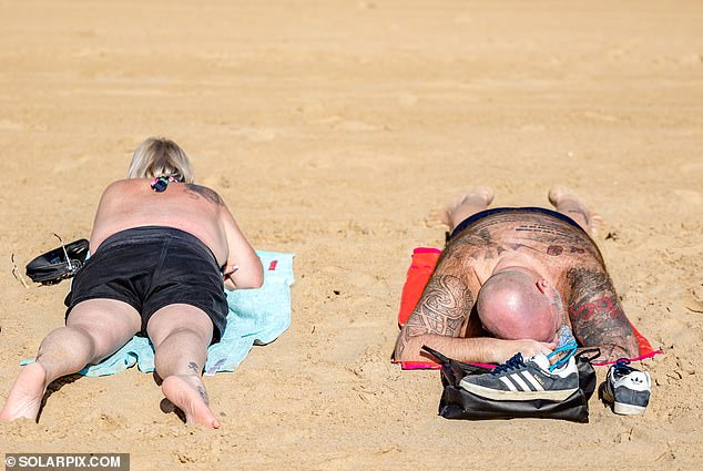 A couple is seen sunbathing on the beach in Benidorm as Spain soaks up the winter rays