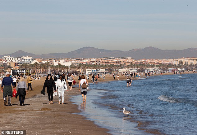 People walk along the seafront on Malvarrosa beach in Valencia, Spain on Thursday