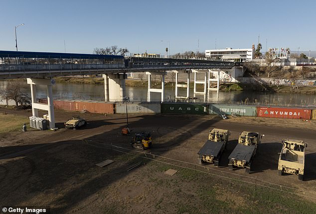 Military vehicles are stationed near shipping containers blocking all access to the Rio Grande riverbank