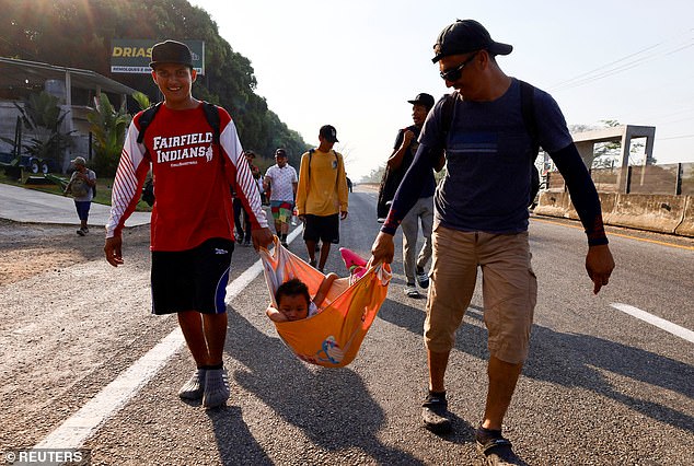 Migrants carry a child while walking in a caravan in Huixtla, Mexico, on Friday after it formed a day earlier.  The group consists of about 1,500 people, most from Central and South America, who planned to rest in Huixtla on Friday and then continue their journey to the town of Escuintla on Saturday.