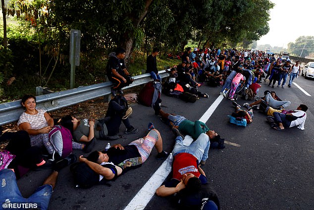 Migrants, most from Central and South America, lie on the sidewalk in Huixtla, Mexico, on Friday, on their second day of their 1,000-mile journey to the U.S. border