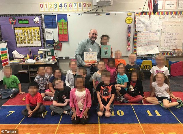 Stultz sits in a chair while reading a book to his students during storytime