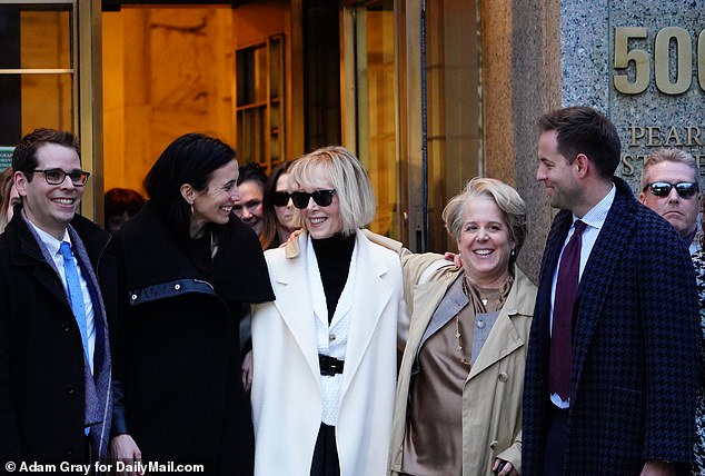 E. Jean Carroll, in white, is seen leaving court in Manhattan with her friends and legal team on Friday evening