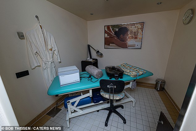 A creepy spa room is seen in ghostly light, with equipment still on the bed and a dressing gown on the wall