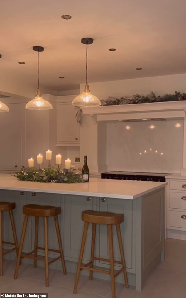 The kitchen panels were painted a fresh white, having ditched the previous baby pink look.  Maisie's new cooking room features a large kitchen island with a striking breakfast bar, three rustic bar stools and a beautiful candle feature