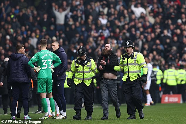 A fan is taken away by police officers after trouble breaks out between fans during the fourth round of the English FA Cup