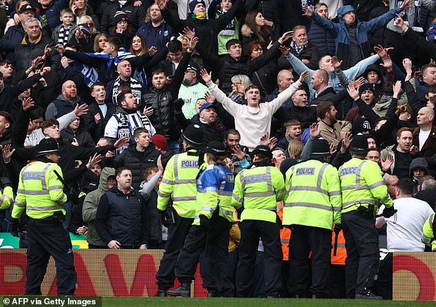 Police and stewards line the edge of the pitch after trouble breaks out between fans during the English FA Cup