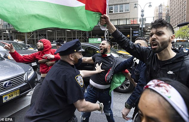 An NYPD office is seen trying to stop angry pro-Palestinian protesters during a demonstration in New York