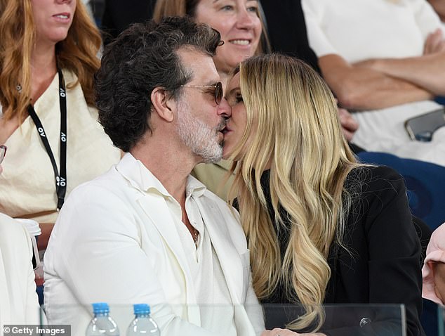 The leggy wellness expert was all smiles as she gazed lovingly at her husband before moving in for a passionate smooch at the Australian Open on Thursday