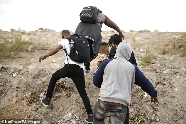 Migrants with children cross Rio Bravo from Mexico to the US