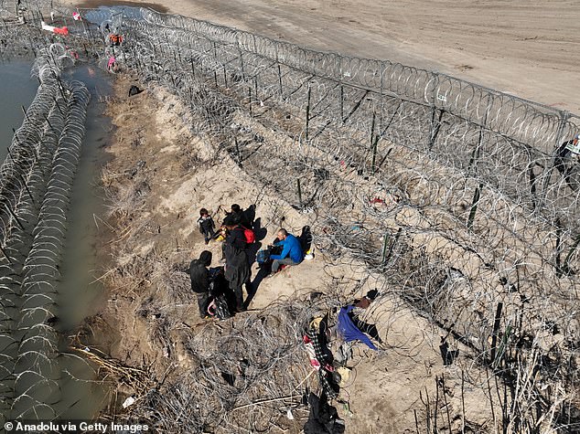 An aerial view of Eagle Pass, Texas, as migrants walk past barbed wire after crossing the Rio Grande into the United States