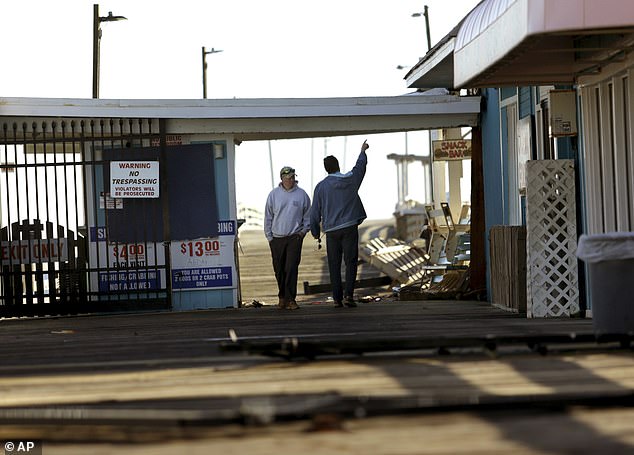 People stand at the spot where a car crashed through a fence at the Virginia Beach Fishing Pier