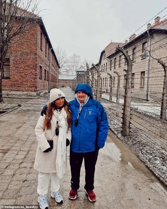 Zoe from Ireland smiled for a photo at the metal fence of the former concentration and extermination camp and described the experience as 'harrowing'