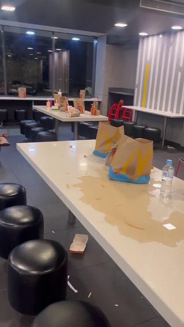 The McDonald's dining area is littered with empty containers and food and drinks have been spilled on the tables and floor