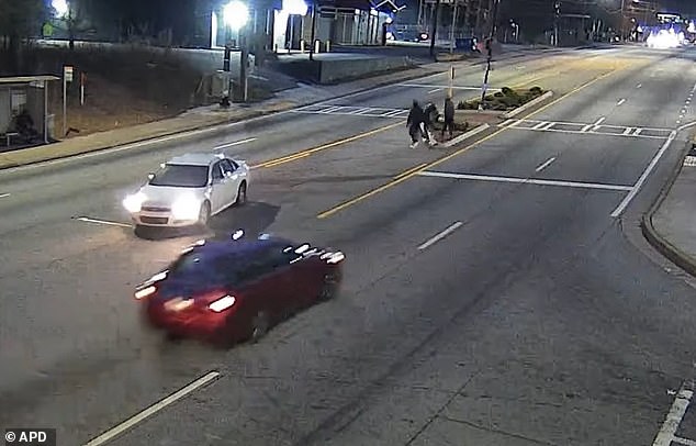 Pictured: The three mysterious gunmen crossing the divided highway before opening fire on the fleeing 11-year-old boy