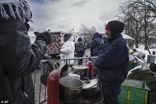 Roberto Medina serves chicken and hot chocolate from a makeshift food stand outside a migrant shelter on New York's Randalls Island on Friday, January 19, 2024