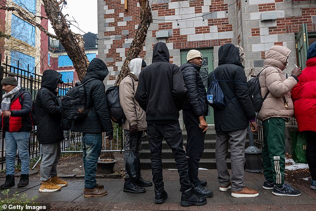 People, mostly newly arrived migrants, receive a midday meal from Trinity Services and Food For the Homeless on January 24, 2024, across from Tompkins Square Park