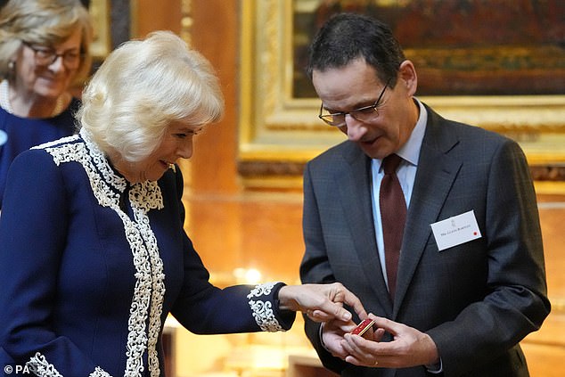 The Queen looked cheerful as she examined a small book made for a dollhouse and presented to her by Glenn Bartley