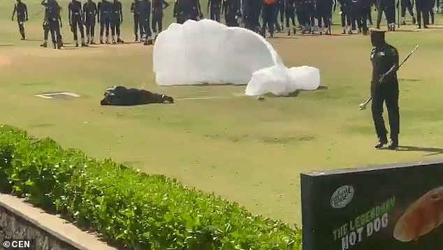 The injured parachutist rolls onto his side and gets on all fours before his colleagues roll him back onto his back and begin to release him from the harness